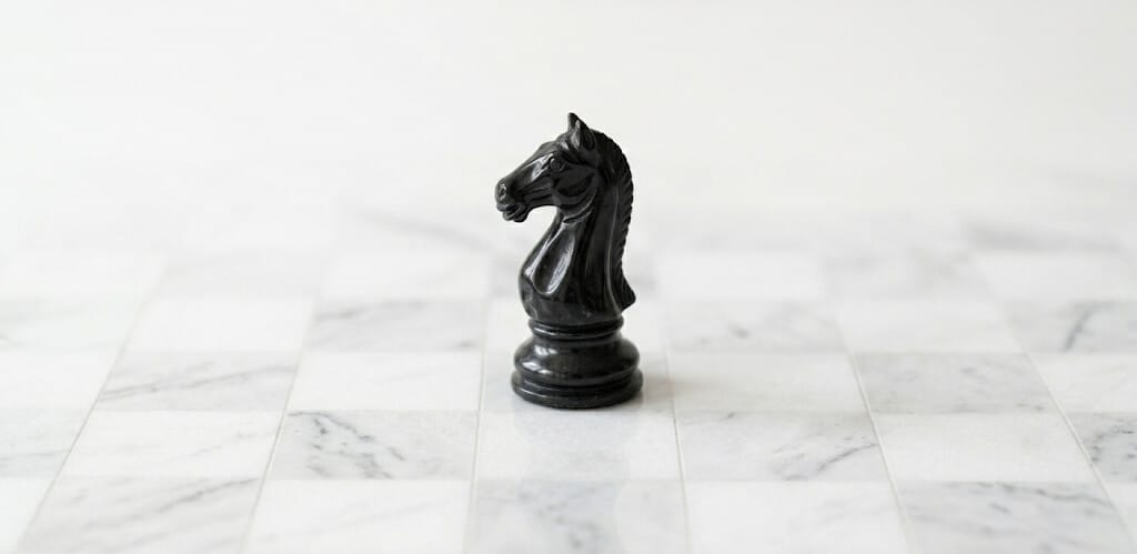 A close-up of a chess piece moving across a clean, white board to represent strategic differentiation